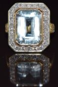 An 18ct gold ring set with an emerald cut aquamarine of approximately 12.3ct surrounded by