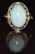A 9ct gold ring set with a jadeite cabochon with a pierced Greek border, 3.3g, size P
