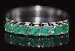 A 14k white gold ring set with seven round cut emeralds, 2.3g, size O