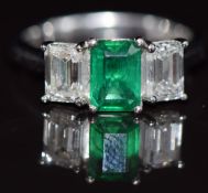 A platinum ring set with an emerald cut emerald of approximately 0.93ct and two emerald cut