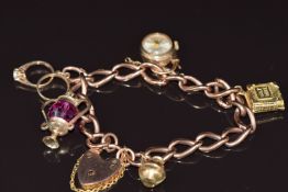 A 9ct rose gold curb link charm bracelet with five 9ct gold charms including bible, rings, jug, lamp