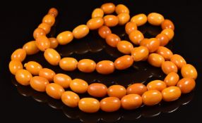 A 1920's Baltic amber necklace made up of 60 butterscotch / egg yolk coloured oval beads, the