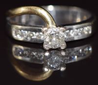 An 18ct gold bi-coloured ring set with a round cut diamond of approximately 0.4ct and further