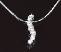 An 18ct white gold pendant set with seven graduated diamonds, the largest approximately 0.13ct, on