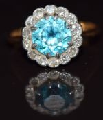 An 18ct gold ring set with a round cut zircon surrounded by diamonds in a platinum setting, 3.9g,