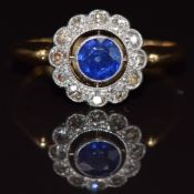 An 18ct gold ring set with a round cut sapphire surrounded by diamonds, 2.7g, size M