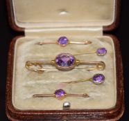 A cased set of three 9ct gold blouse pins/ brooches and two 9ct gold stick pins set with amethysts