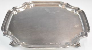 George V hallmarked silver salver with incuse corners, raised on four scroll feet, Sheffield 1933,