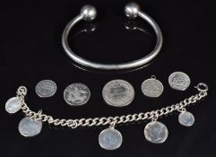 A silver bangle, silver bracelet with coin charms and three silver coins