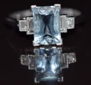 An 18ct white gold ring set with an aquamarine and two baguette cut diamonds to each shoulder, 4.6g,