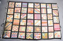 A large rug with forty individual guls against a black ground, some with figural decoration, 244 x