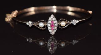 A late Victorian / early Edwardian bangle set with three rubies surrounded by old cut diamonds in