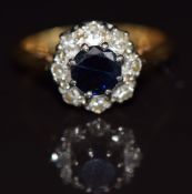An 18ct gold ring set with a round cut sapphire of approximately 0.7ct surrounded by diamonds, 4.5g,
