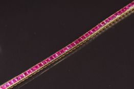 An 18ct gold tennis/ line bracelet set with seventy calibre cut rubies measuring approximately 0.