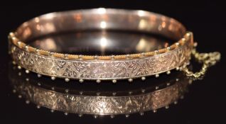 A 9ct gold bangle with engraved foliate decoration and spheres to the border, in Charles Horner box,