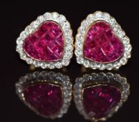 A pair of 18ct gold earrings each in the form of a heart set with calibre cut rubies surrounded by