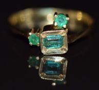 An 18k gold ring set with an emerald cut emerald and two round cut emeralds, 2.1g, size P