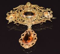 A 19thC filigree brooch set with three oval cut imperial topaz and a drop section set with a further