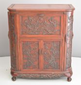 Chinese carved cocktail cabinet with lift up flap and mirrored interior and cellarette base to