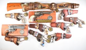 Eleven replica revolvers and revolver wall plaques including Bradford Exchange John Wayne Cowboy