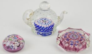 Three glass paperweights comprising two John Deacons one in the form of a teapot with control bubble