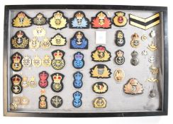 Mounted display of approximately 40 Royal and Merchant Navy cap badges including officer's hat and