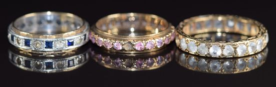 Three 9ct gold eternity rings, one set with pink sapphires (missing stone), one sapphires and spinel