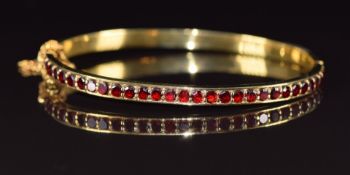 A 9ct gold bangle set with garnets, 14g, 6 x 5.1cm