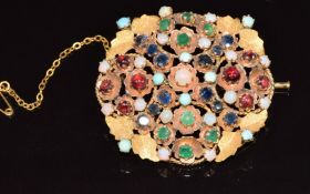 A 9ct gold brooch set with turquoise, opals, emeralds, sapphires and garnets, with textured