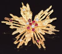 An 18ct gold pendant / brooch in a textured starburst design set with rubies and diamonds, by