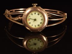 A 9ct rose gold ladies bangle wristwatch with blue hands, Roman numerals, gilt decorated white
