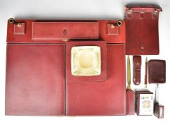 Etienne Aigner red leather library desk set comprising desk stand with fold out cover, tape measure,