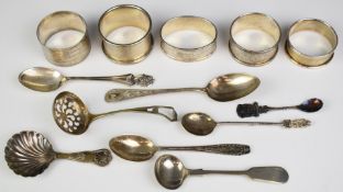 Four hallmarked silver napkin rings and a further example marked sterling silver, together with