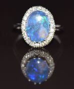 An 18ct white gold ring set with a black opal surrounded by diamonds, the total diamond weight