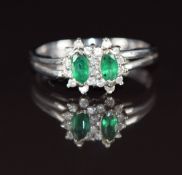 An 18k white gold ring set with two marquise cut emeralds surrounded by diamonds, 3.1g, size L