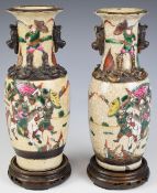 A pair of 19thC Chinese crackle glazed vases with figural warrior decoration with wooden stands,