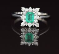 A 9ct white gold ring set with an emerald cut emerald of approximately 0.2ct surrounded by diamonds,