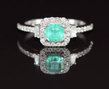 An 18k white gold ring set with an emerald cut emerald of approximately 0.7ct, two baguette cut