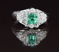 A platinum ring set with an emerald cut emerald of approximately 0.75ct surrounded by diamonds,