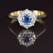 An 18ct gold ring set with a round cut sapphire of approximately 0.4ct surrounded by diamonds in a