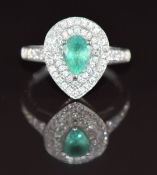 An 18k white gold ring set with a pear cut emerald of approximately 0.6ct surrounded by two rows