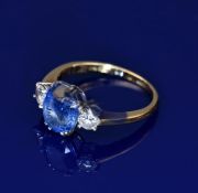 An 18ct gold ring set with an oval cut sapphire of approximately 3.1ct and two diamonds, each