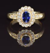 An 18ct gold ring set with an oval cut sapphire of approximately 0.7ct surrounded by diamonds, 6.4g,