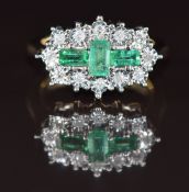 A 9ct gold ring set with three emerald cut emeralds totalling approximately 0.69ct and diamonds