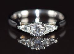 A platinum ring set with a round brilliant cut diamond of approximately 0.35ct and two pear cut