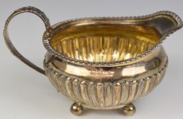 Georgian hallmarked silver milk jug with reeded lower body, raised on four ball feet, London 1817,