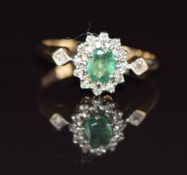 A 9ct gold ring set with an oval cut emerald and diamonds, 1.9g, size L