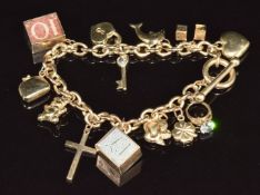 A 9ct gold charm bracelet with eleven 9ct gold charms including 10 shilling note, £1 note, four leaf