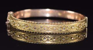 A 9ct gold bangle with applied decoration and rope twist border, 9.2g, 5.4 x 4.5cm