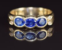 An 18ct gold ring set with three oval cut sapphires, each approximately 0.3ct and four diamonds, 4.